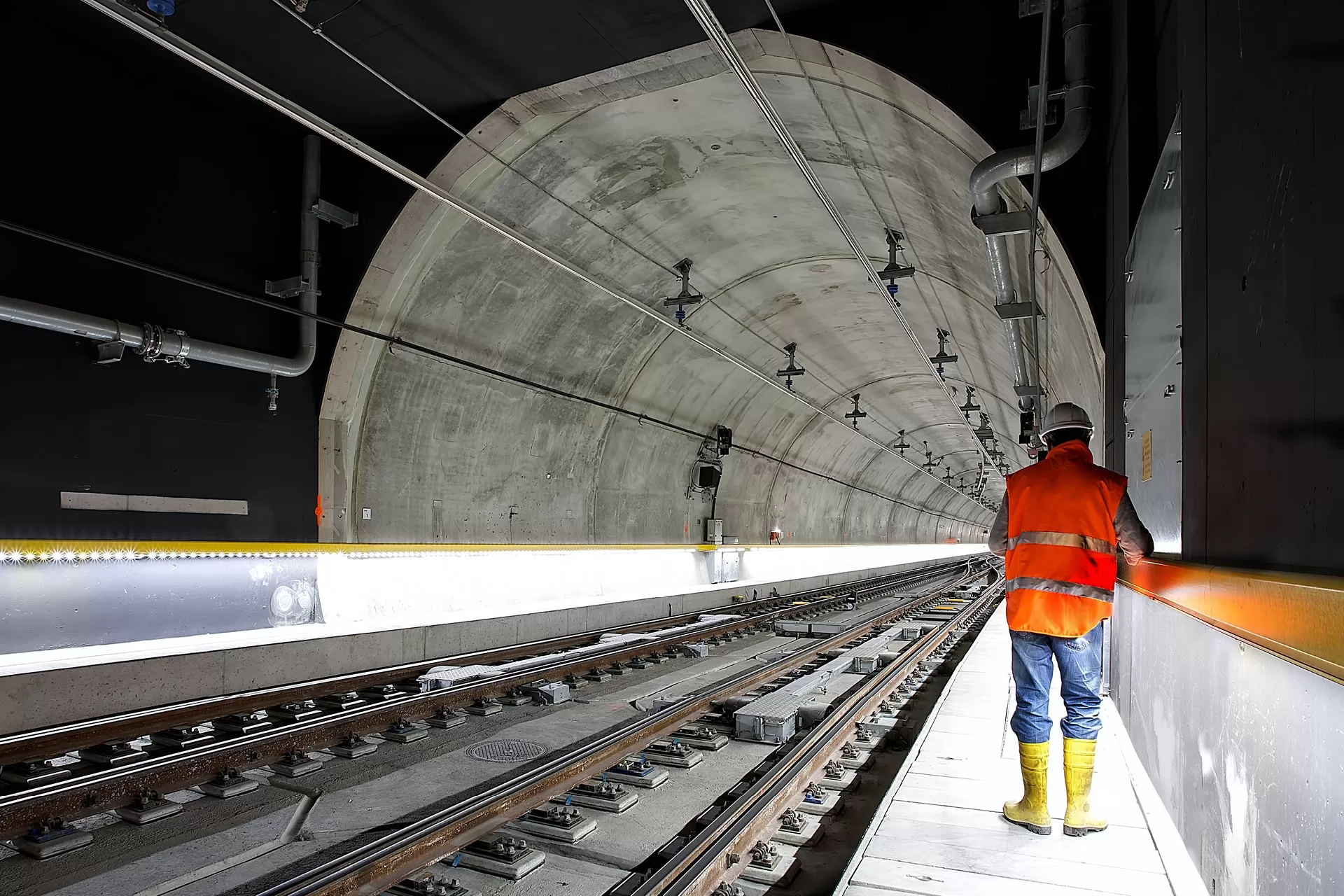 Ein Mann in Bauarbeiter-Schutzkleidung steht in einem neuen Zugtunnel neben den Gleisen.