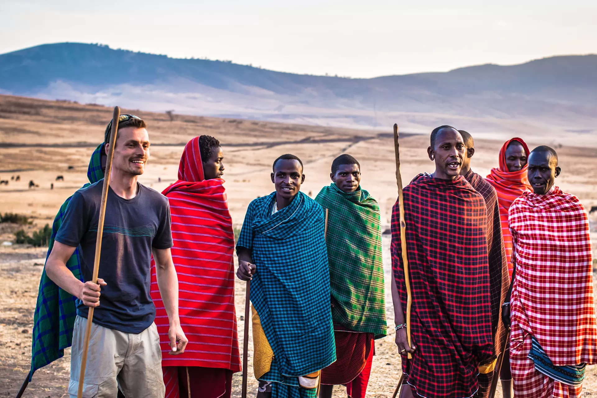 Ein europäischer Mann zu Besuch bei einer Gruppe Massai-Männern.