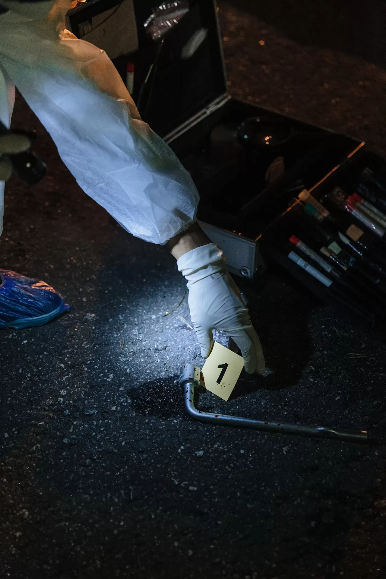 Bei einer Tatortuntersuchung legt die Spurensicherung eine Nummer neben die mögliche Tatwaffe am Boden.