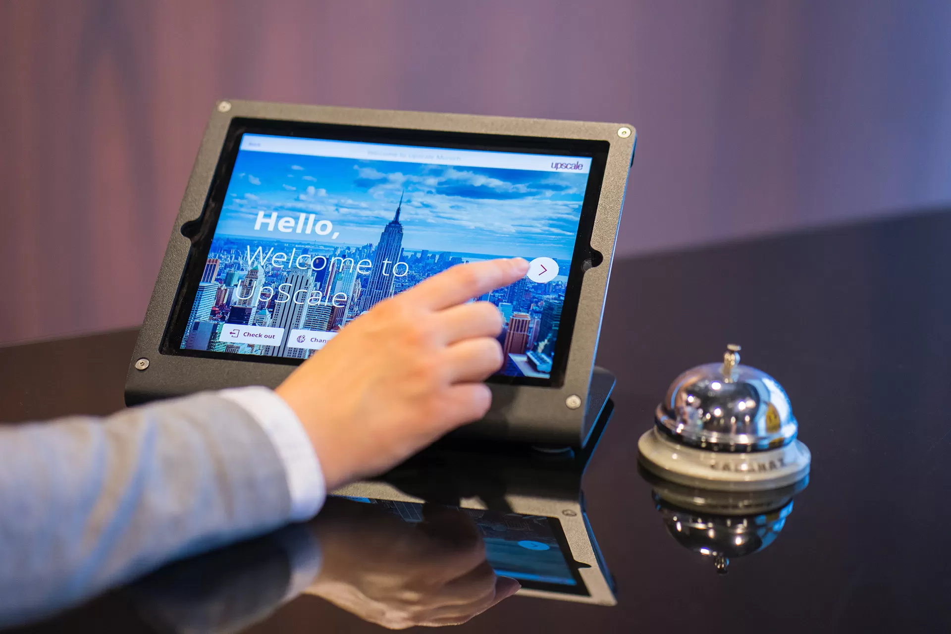 Digitales Check-In über Tablet an Hotelreception, daneben steht Tischglocke / Receptionsglocke.