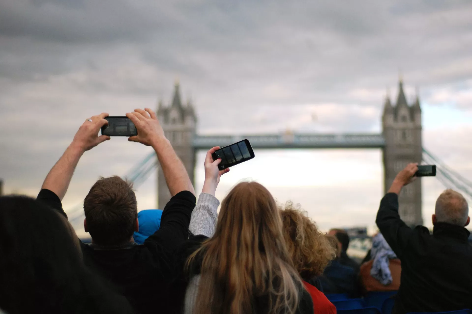 Personen einer Touristengruppe in London, die die Towerbridge in London mit dem Smartphone fotografieren.