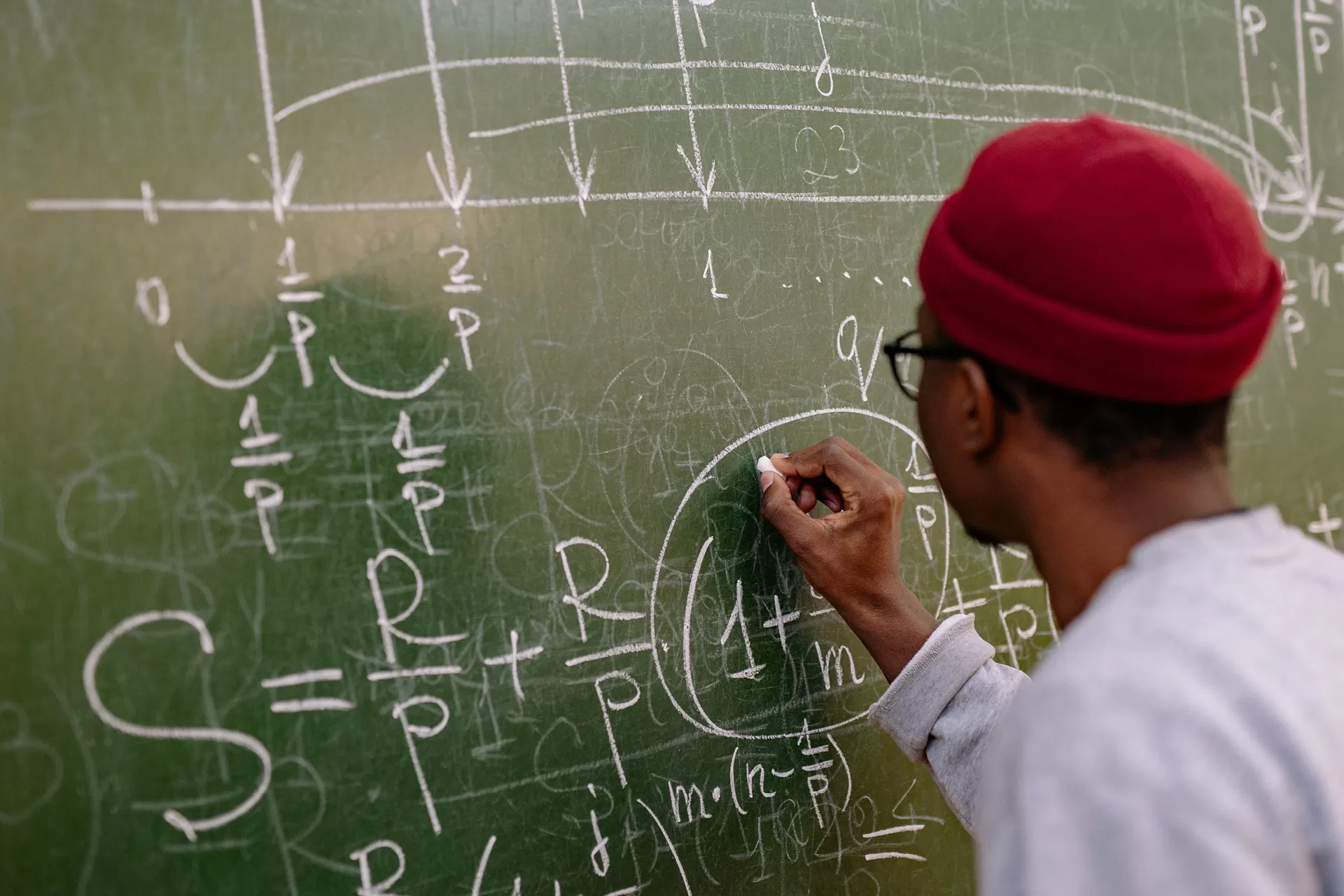 Ein Mann schreibt eine Formel auf eine Wandtafel.