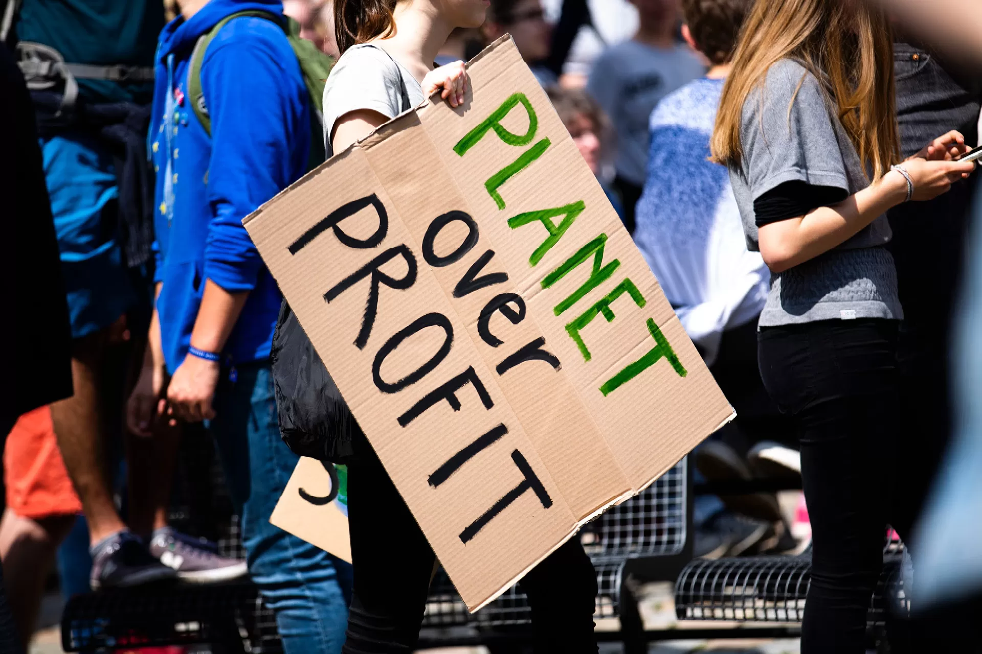 Junge Frau trägt ein Pappschild am globalen Klimastreik mit der Aufschrift «PLANET over PROFIT».