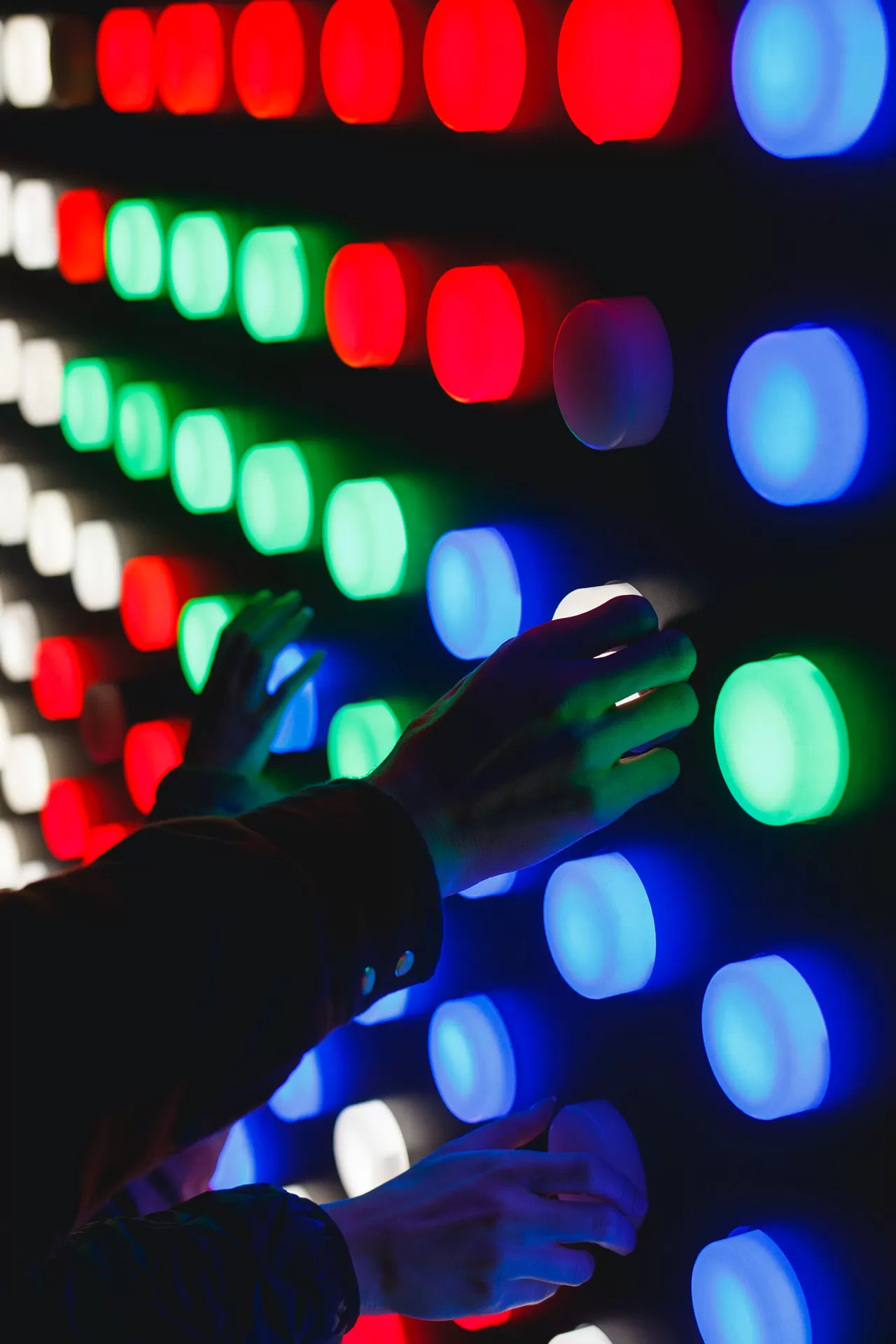 Interaktive Wand mit farbigen Lichtern und Hände die damit spielen.