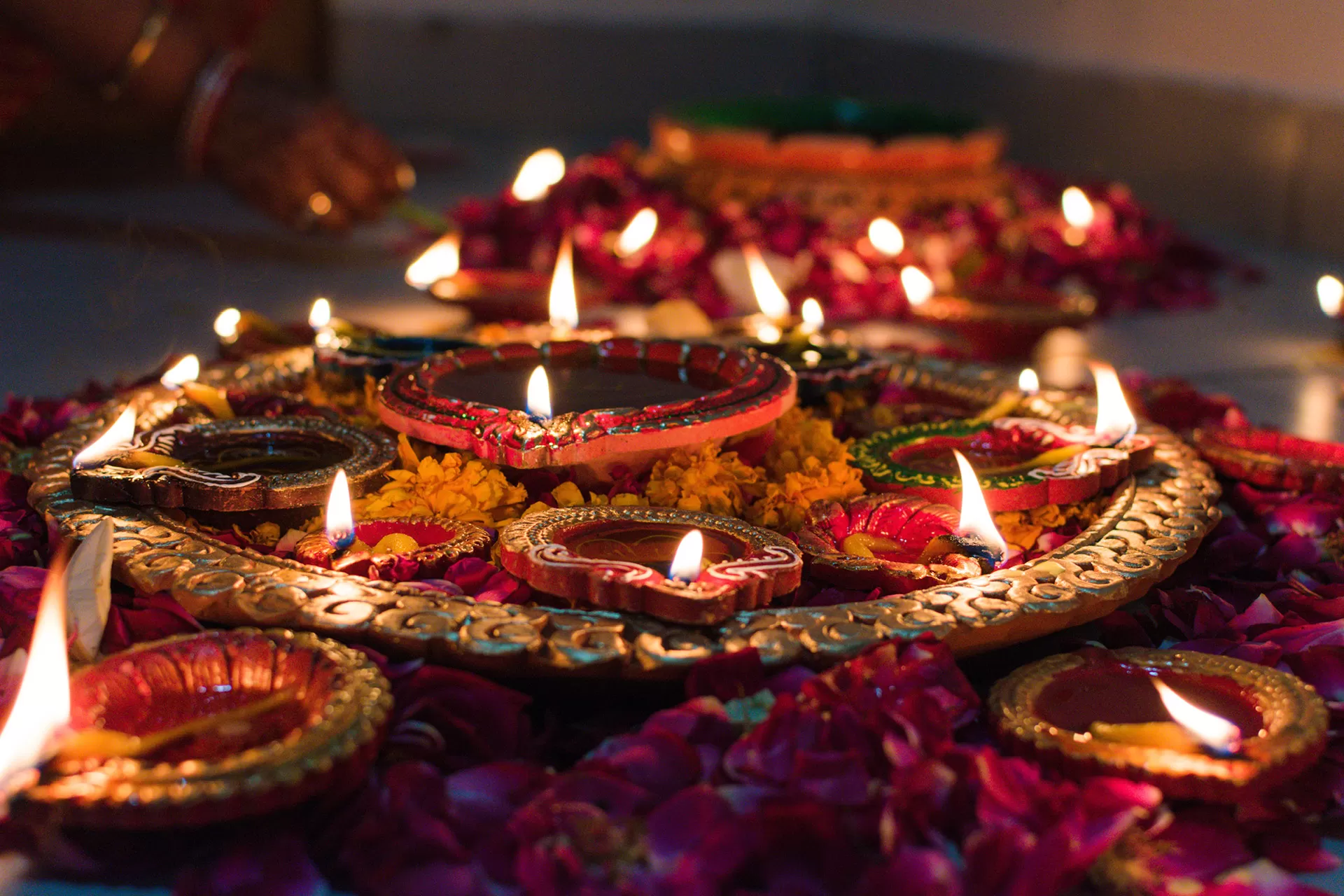 Brennende Kerzen und farbige handgefertigte Öllampen aus Ton, die zusammen mit Blumen für Diwali ausgelegt sind.