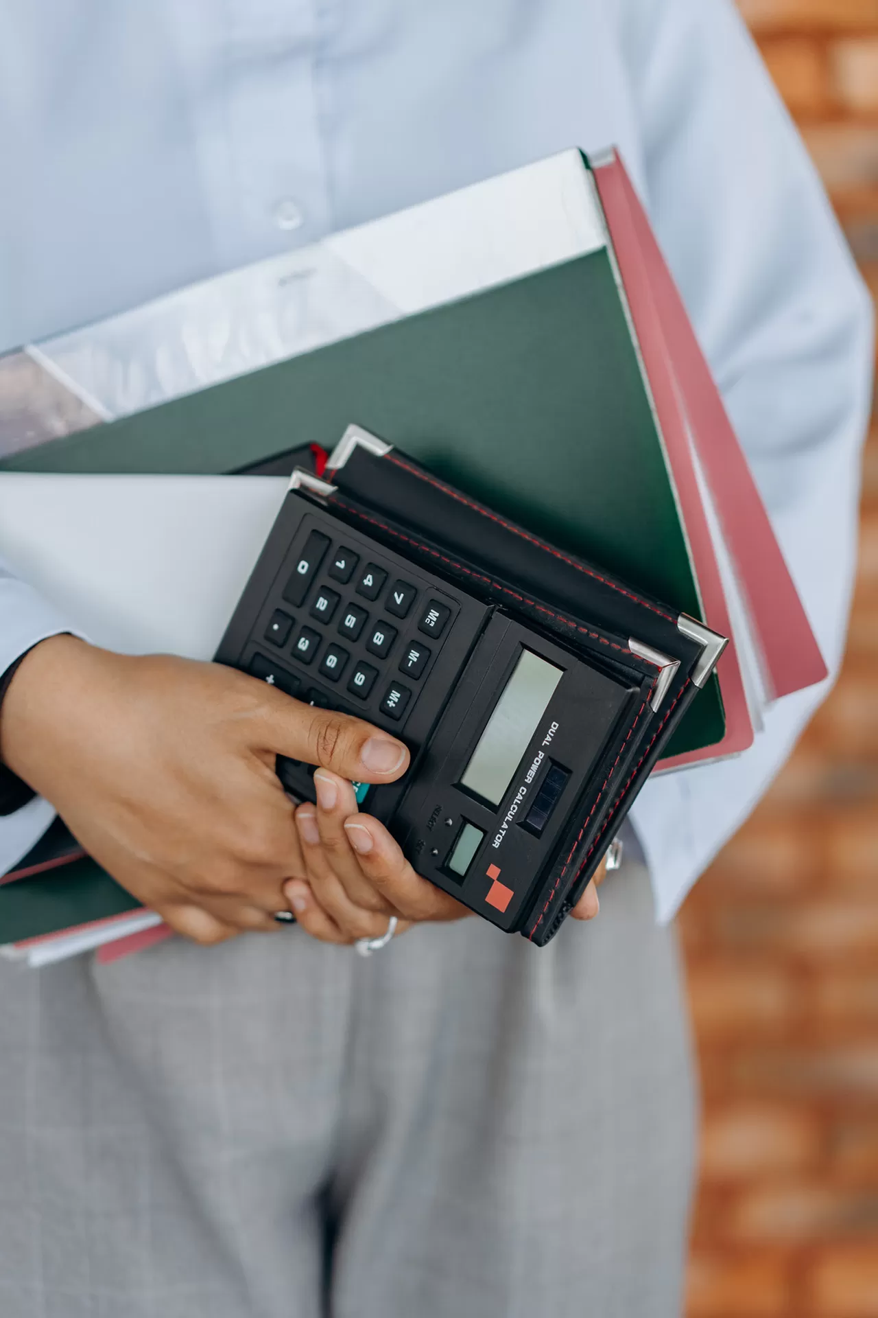 Eine Geschäftsfrau hält Papierunterlagen und Taschenrechner in den Händen.
