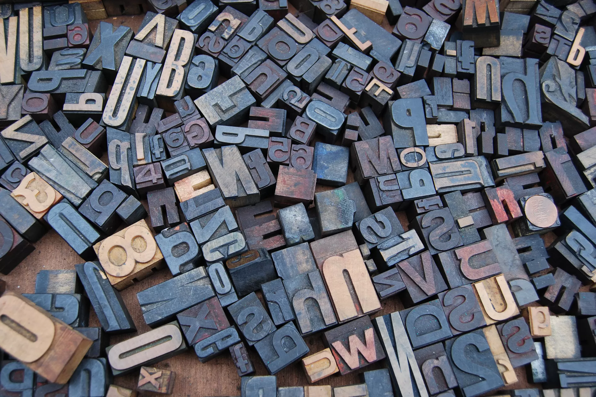 Holzdruckbuchstaben in unterschiedlichen Grössen liegen auf einem Tisch. Sie werden für Letterpress oder Buchdruck benötigt.