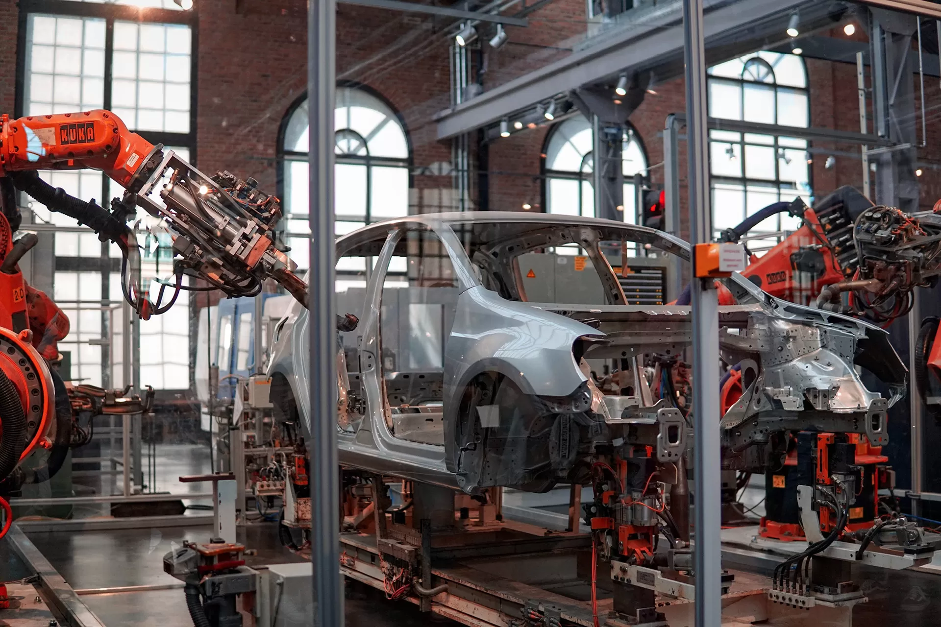 Aufnahme in einer Automobil-Industriehalle, wo ein Produktionsschritt von grossen Roboterarmen ausgeführt wird.