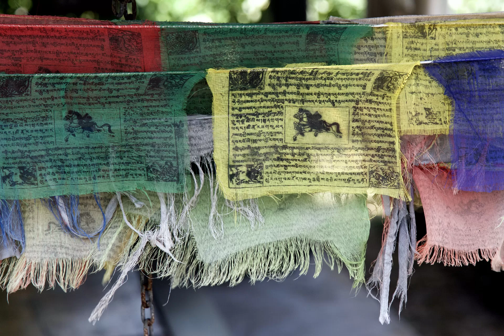 Eine aufgehängte Wimpelkette mit farbigen Tibetischen Gebetsflaggen.