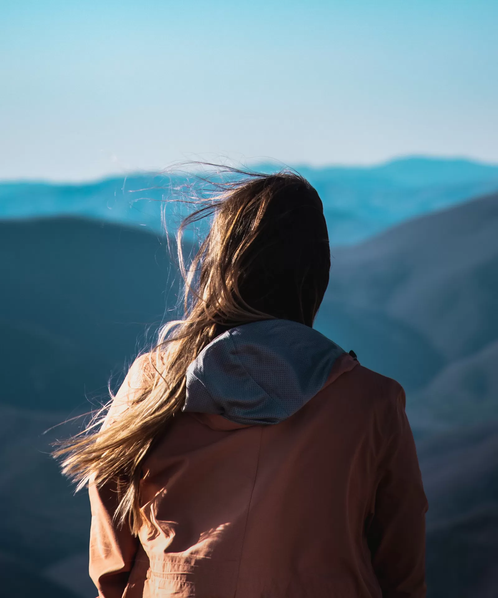Eine junge Frau schaut in die Ferne über Berge zum Horizont.