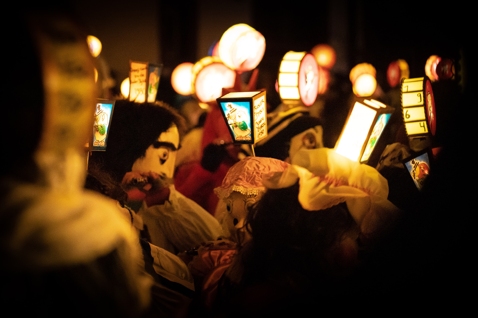 Morgenstreich der Basler Fasnacht: verkleidete Personengruppe im Dunkeln mit Larven/Masken und Laternen.