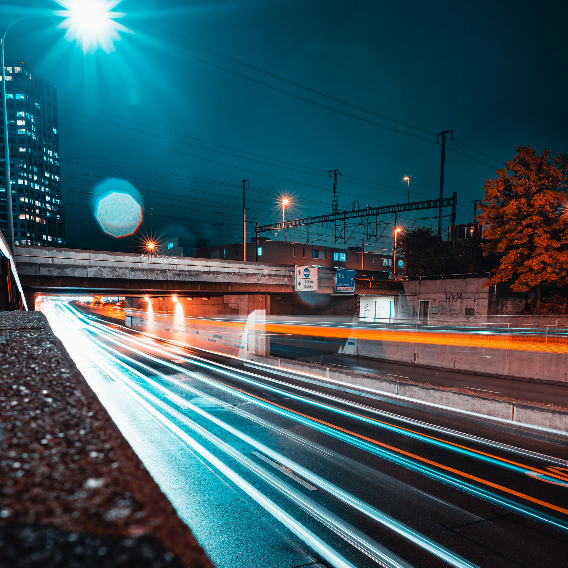 Nächtliche Aufnahme einer Strasse, bei der die Lichter der Fahrzeuge als Lichtstreifen erscheinen.