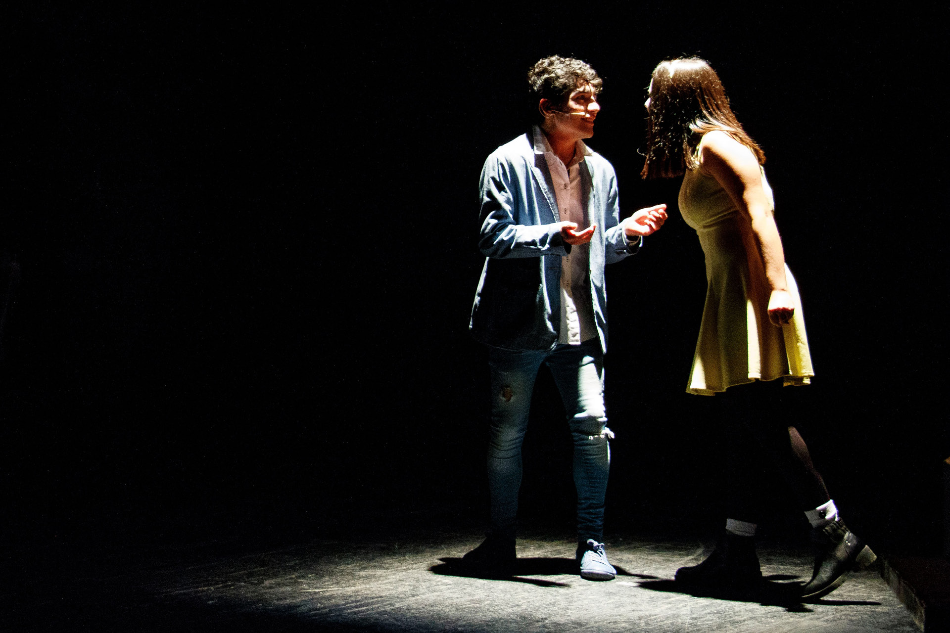 Zwei Schauspieler im Spotlight während einem Theaterauftritt.