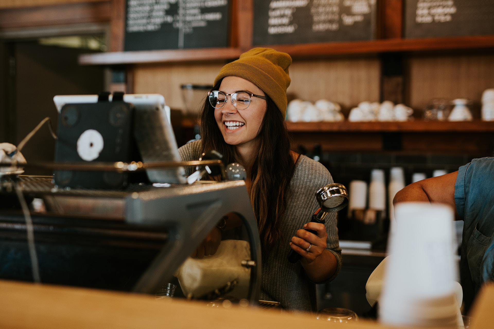 Junge gutgelaunte Barrista arbeitet an der Kaffeetheke.